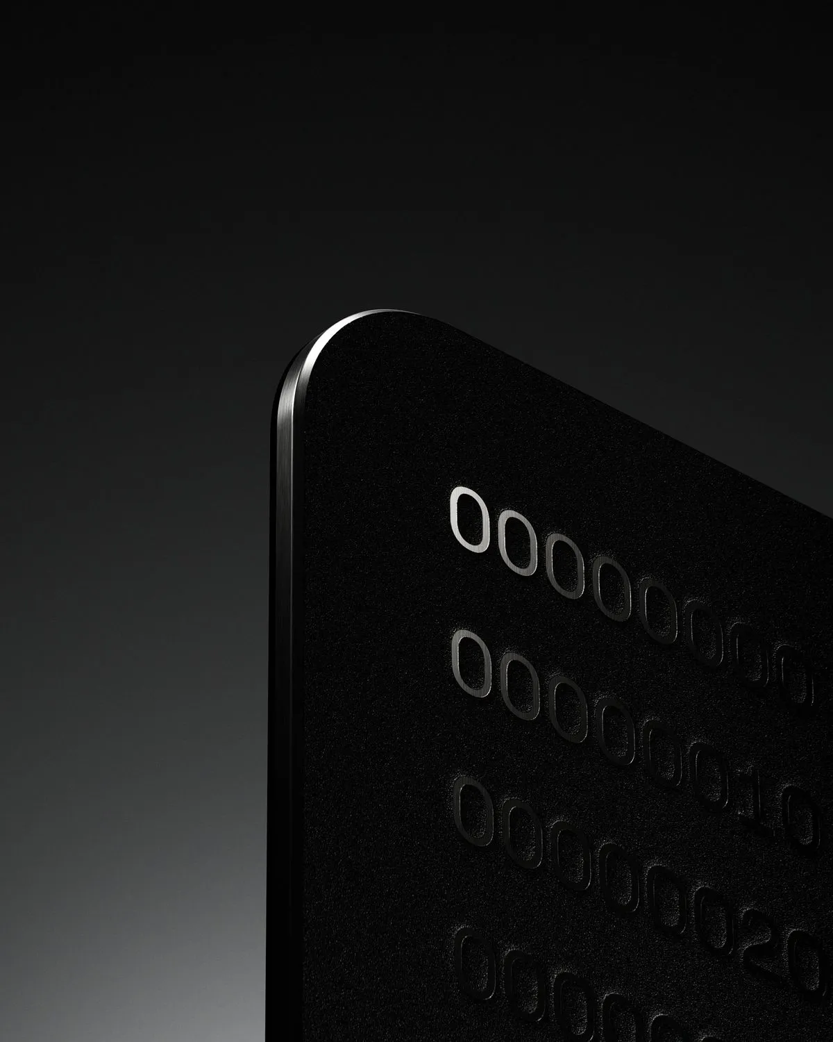 Close-up of a black card corner with embossed numbers on its surface against a dark background.