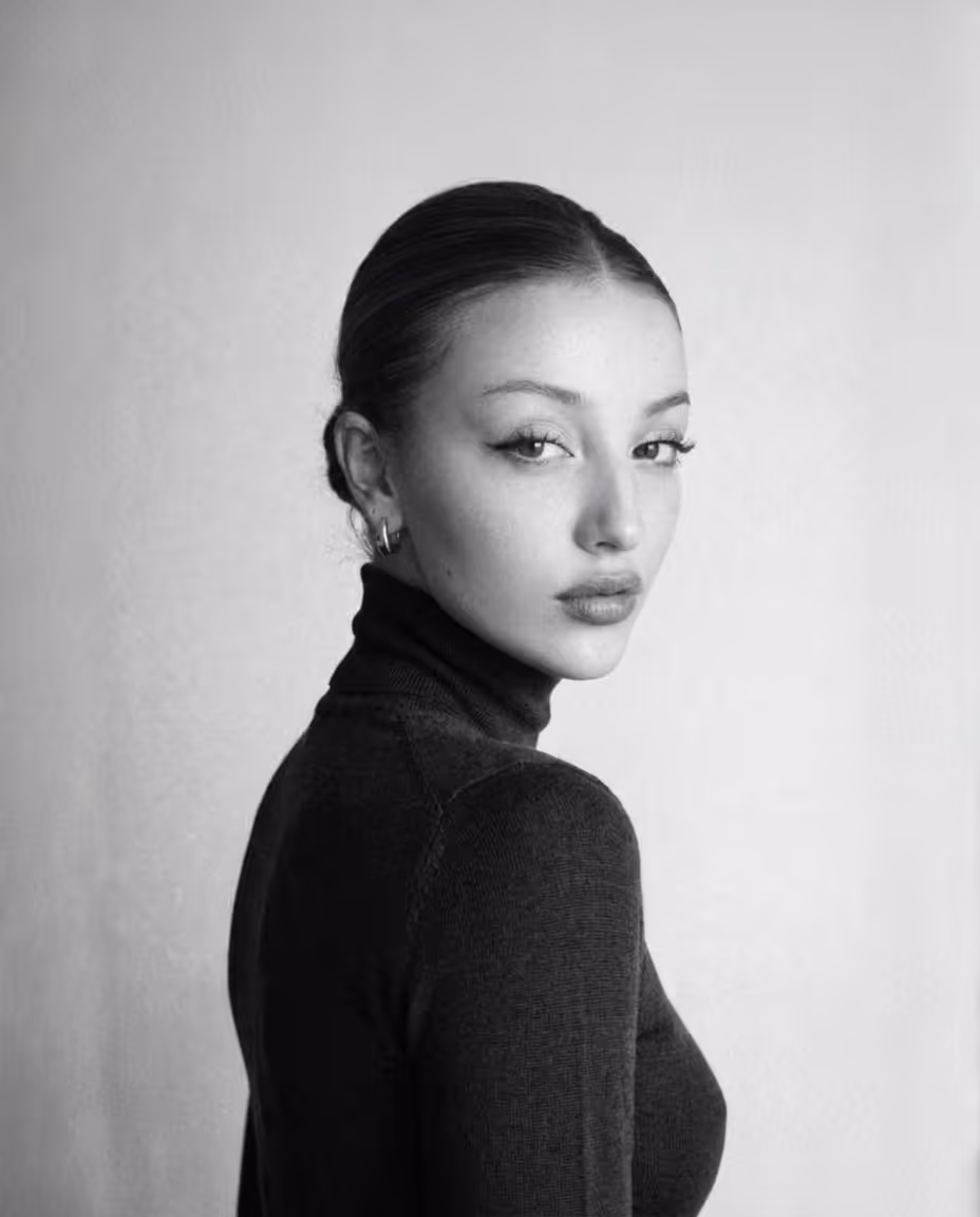 Portrait en noir et blanc d'une femme avec un chignon et un col roulé sombre.