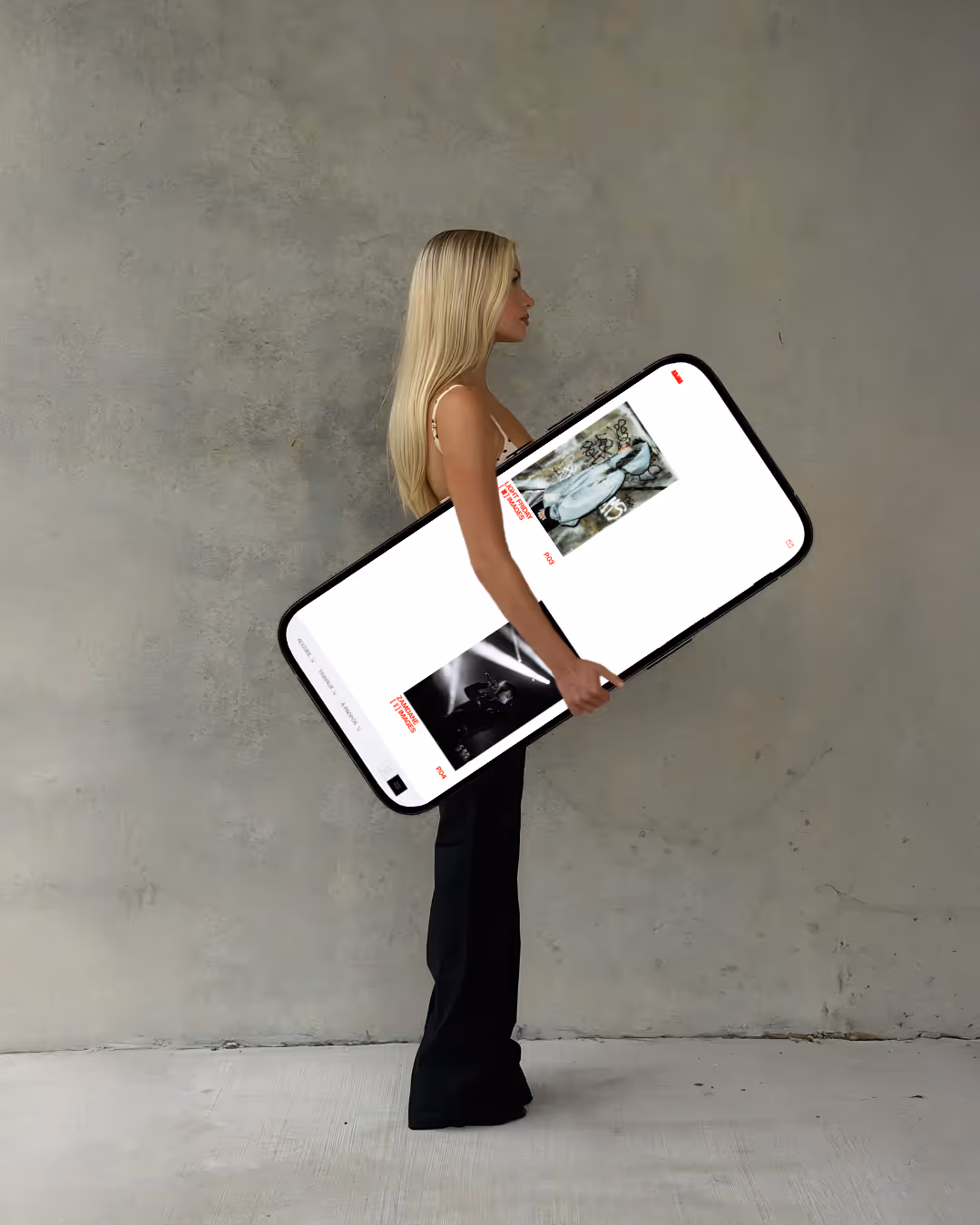 Femme tenant un téléphone géant affichant des images sur un fond gris neutre.