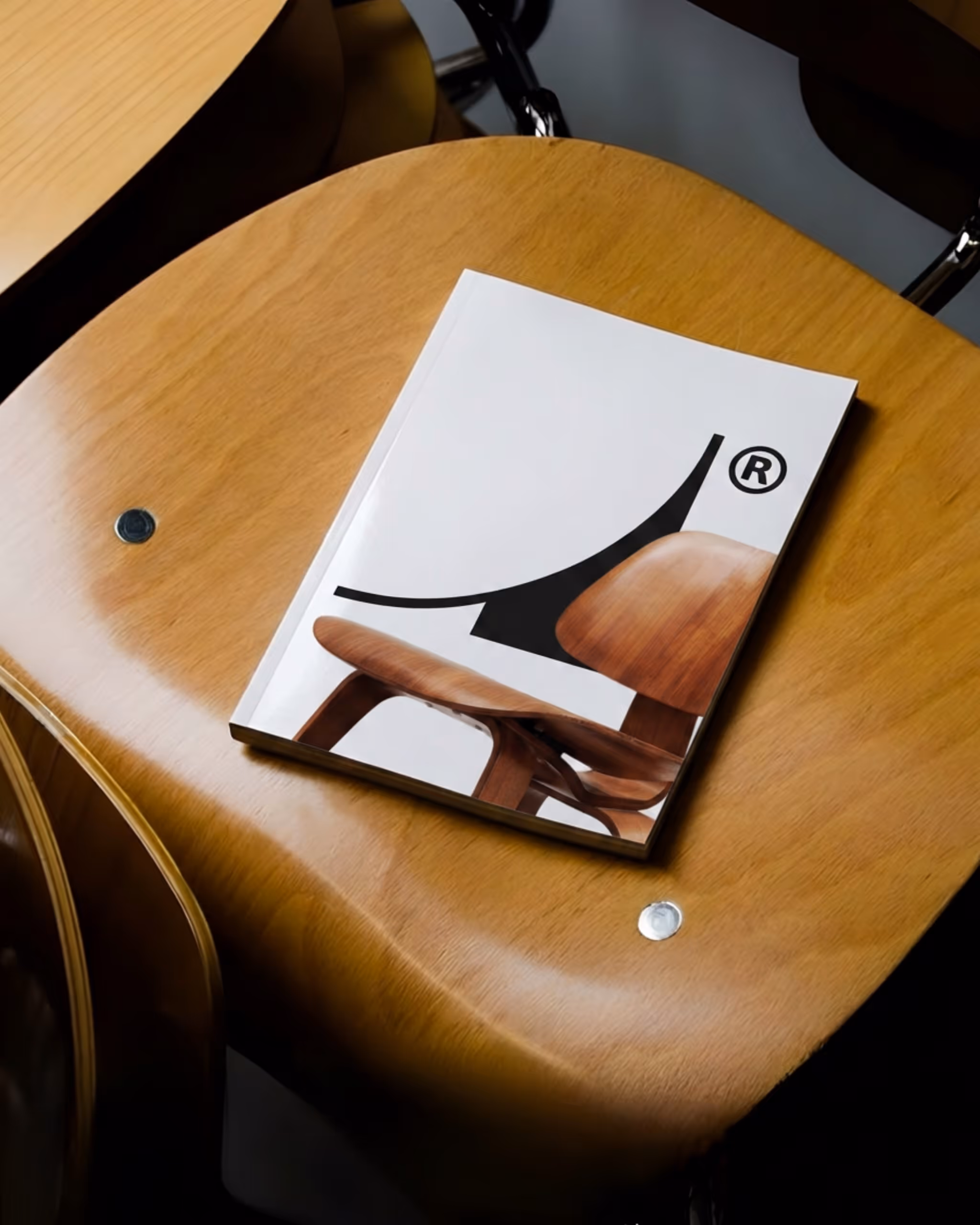 Un magazine avec une image partielle d'une chaise en bois sur une table en bois clair.