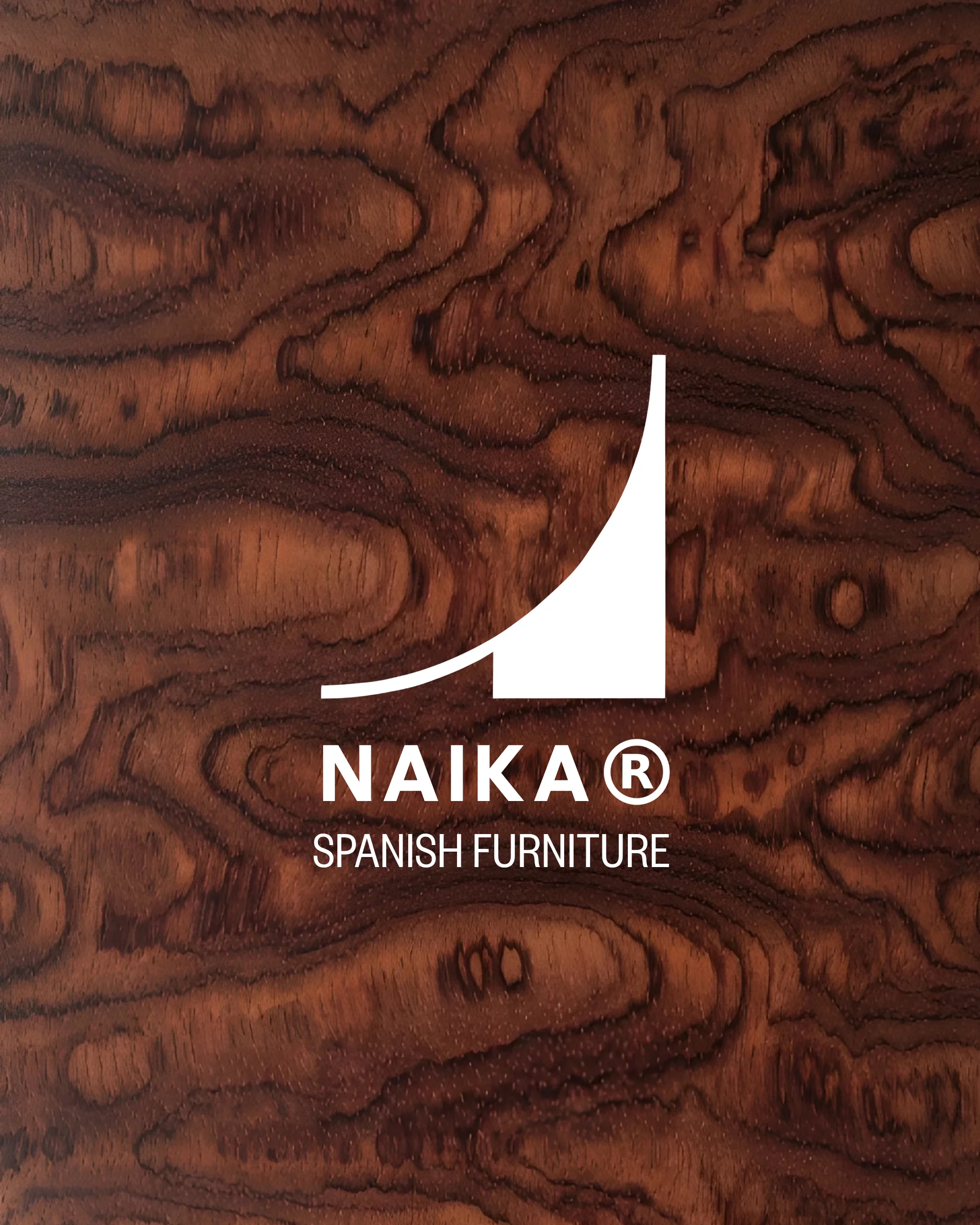 Logo blanc NAIKA® avec texte 'Spanish Furniture' sur un fond de bois foncé à grains visibles.